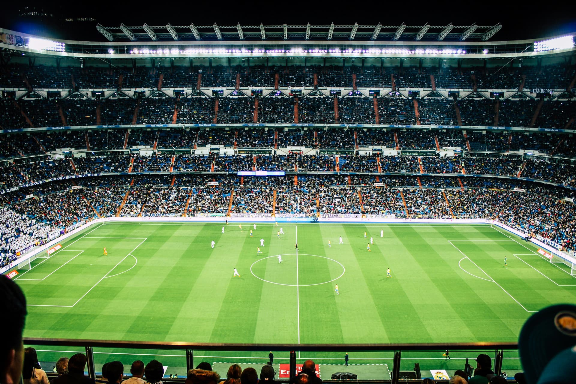 A floodlit football stadium packed with spectators during a match